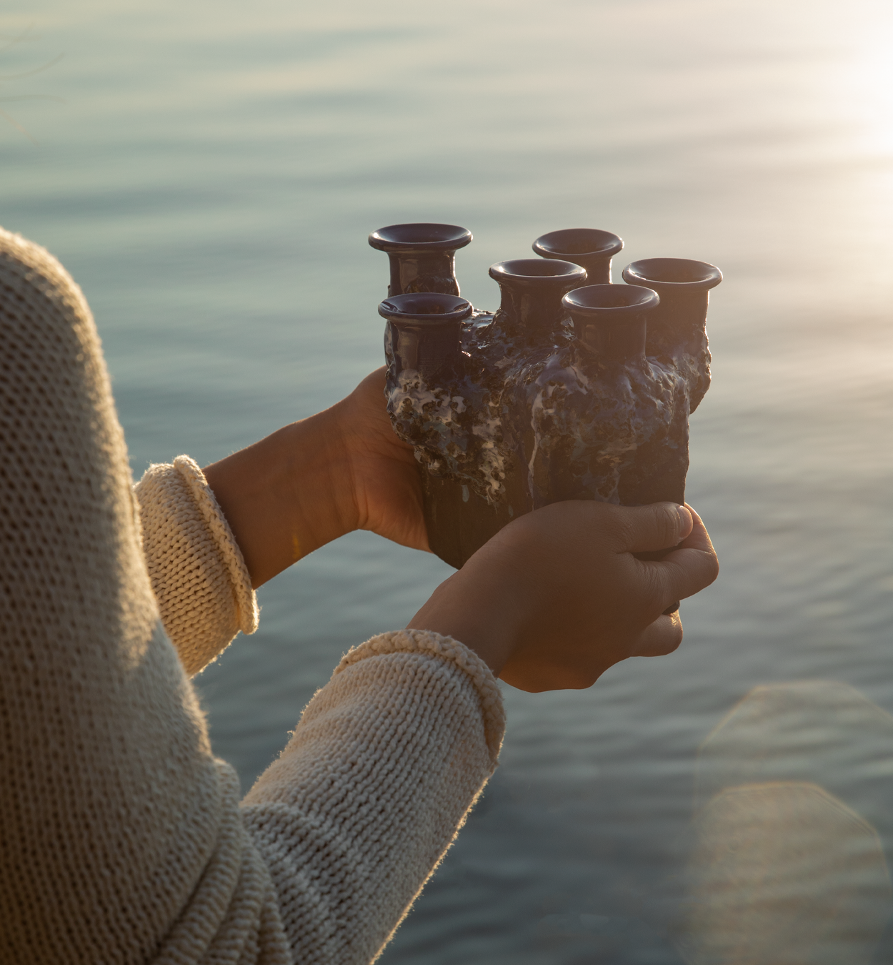 Hands holding a Pentik Kaamoskivi candelabra with calm lake on the background.