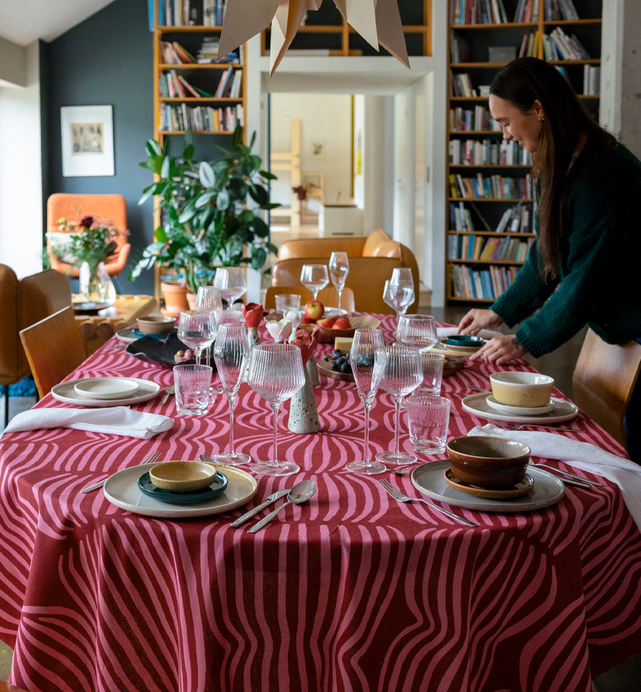 Kuvassa nainen kattaa pöytää, jolla on punainen Vilja-pöytäliina. Ohjaus Joulu 2025 teemasivulle.